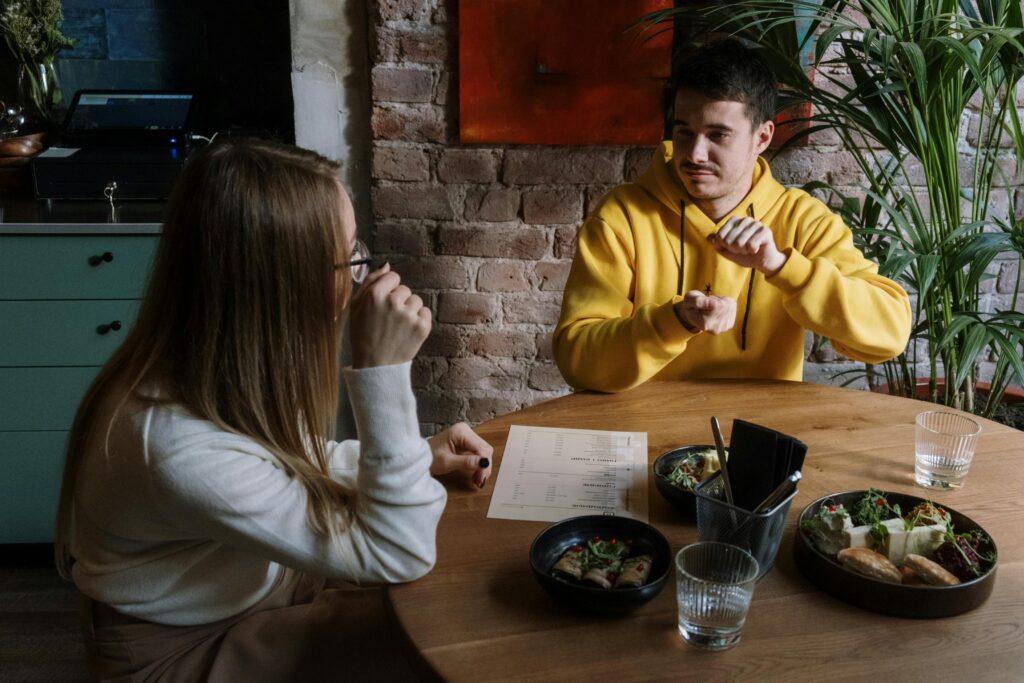 Gebarentaal: Foto door cottonbro studio: https://www.pexels.com/nl-nl/foto/vrouw-in-wit-overhemd-met-lange-mouwen-zit-naast-de-man-in-gele-trui-6322477/